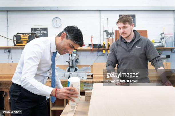 British Prime Minister Rishi Sunak helps to make a wooden door with carpentry apprentice Adam Jellis during a visit to Pinewood Studios on January...