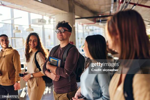 nerdiger männlicher schüler, der mit seinen freunden durch einen schulflur geht. - male student wearing glasses with friends stock-fotos und bilder