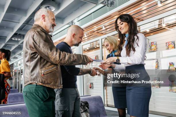 a gaz couple show their boarding passes to airport staff - mature man smiling 40 44 years blond hair stock pictures, royalty-free photos & images