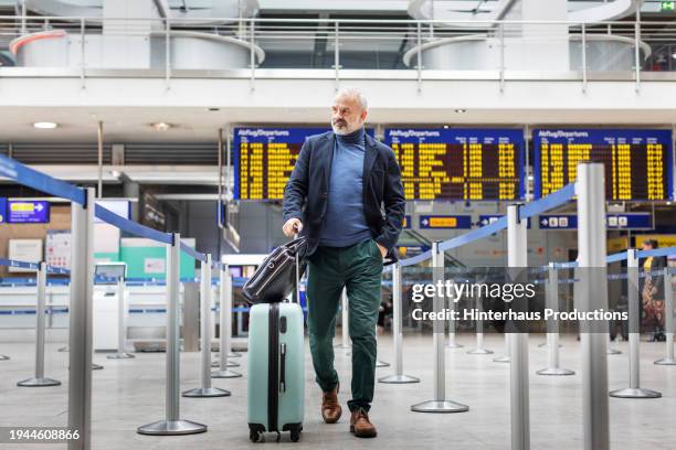a well-dressed man makes his way to an airport check-in - barrikade stock-fotos und bilder