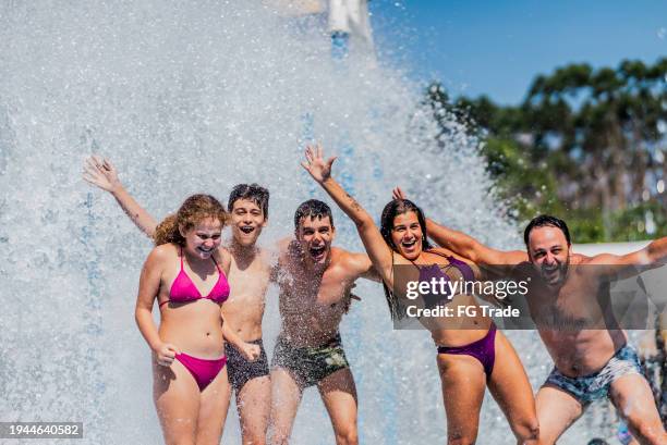 portrait of a family having fun at water park - girls and boys playing in waterpark stock-fotos und bilder