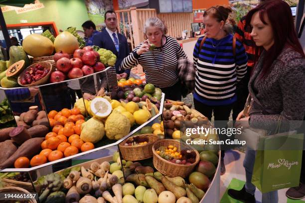 Visitors look at fruits and vegetables on display at the Green Week agricultural trade fair on its opening day on January 19, 2024 in Berlin,...