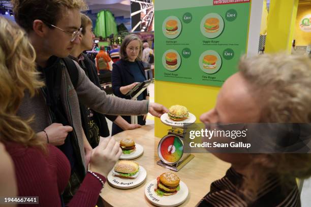 Visitors learn about the climate impact of burger variations, including beef, feta and veggie, at the stand of Germany's Federal Ministry of Food and...