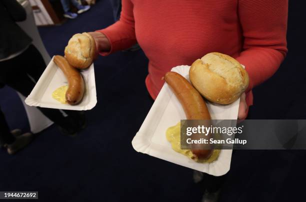 Visitor carries bockwurst sausages with bread and mustard she bought at the Green Week agricultural trade fair on its opening day on January 19, 2024...