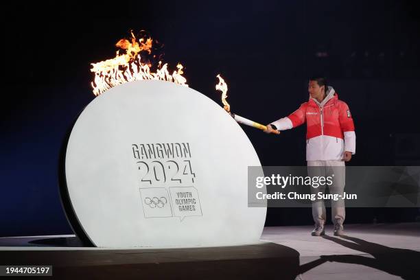 Torch bearer Lee Jeong-min of South Korea, participating athletes representative of 2024 Gangwon, lights the cauldron during the opening ceremony of...