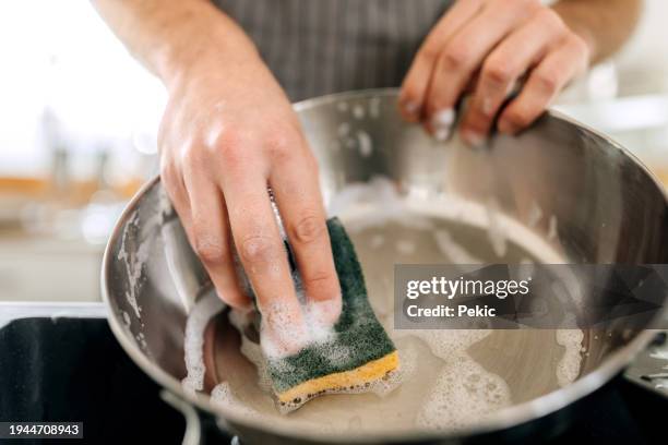 colpo ravvicinato dell'uomo che lava la padella - spugna per le pulizie foto e immagini stock