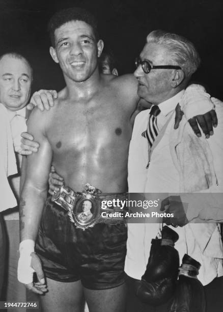 British boxer Randy Turpin, wearing his British light-heavyweight title belt, alongside his manager, George Middleton, who holds a pair of boxing...