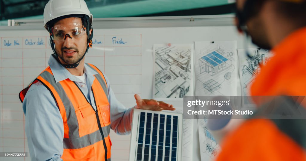 Team von Wirtschaftsingenieuren, die sich mit erneuerbaren Energien treffen und an einer innovativen, effizienteren Solarpanelbatterie in der Produktionsfabrik arbeiten. Technische und nachhaltige Produktionsanlage.