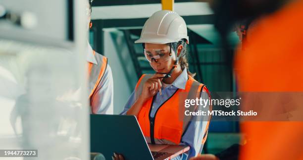 primer plano del equipo de ingenieros industriales que se reúnen, analizan los planos de la maquinaria, consultan el proyecto en la computadora portátil en la fábrica de fabricación. ingeniería y planta de producción sostenible. - seguridad y salud ocupacional fotografías e imágenes de stock
