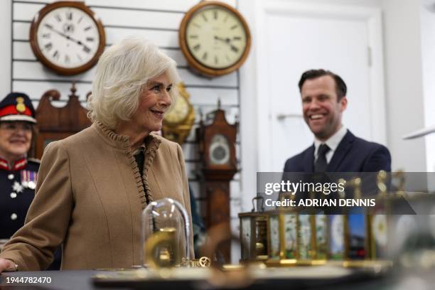 Britain's Queen Camilla looks at a collection of carriage clocks, during a visit to Deacon & Son Jewellers in Swindon, western England, on January 22...