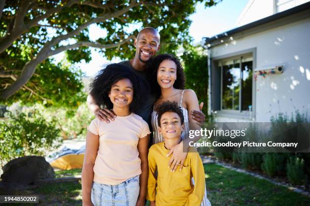 padres sonrientes de pie con sus dos hijos afuera en su patio - parte de una serie fotografías e imágenes de stock