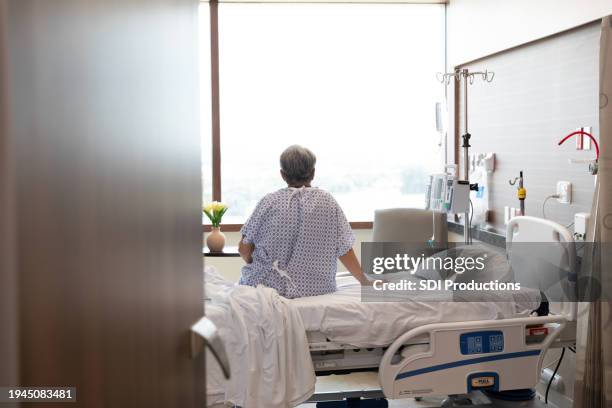 unrecognizable female patient sits on her hospital bed - hospital bed with iv stock pictures, royalty-free photos & images
