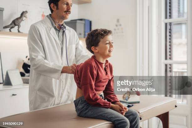 doctor examining young boy - medical examination room stock pictures, royalty-free photos & images