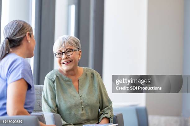 senior adult woman smiles while talking to her doctor - acute care setting stock pictures, royalty-free photos & images