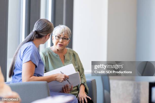 senior adult female patient asks the nurse questions - neurologist stock pictures, royalty-free photos & images
