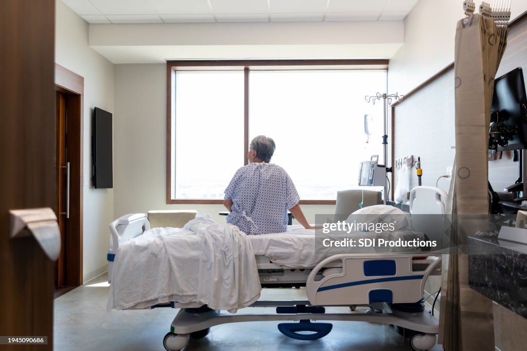 Senior adult woman sits alone in her hospital room