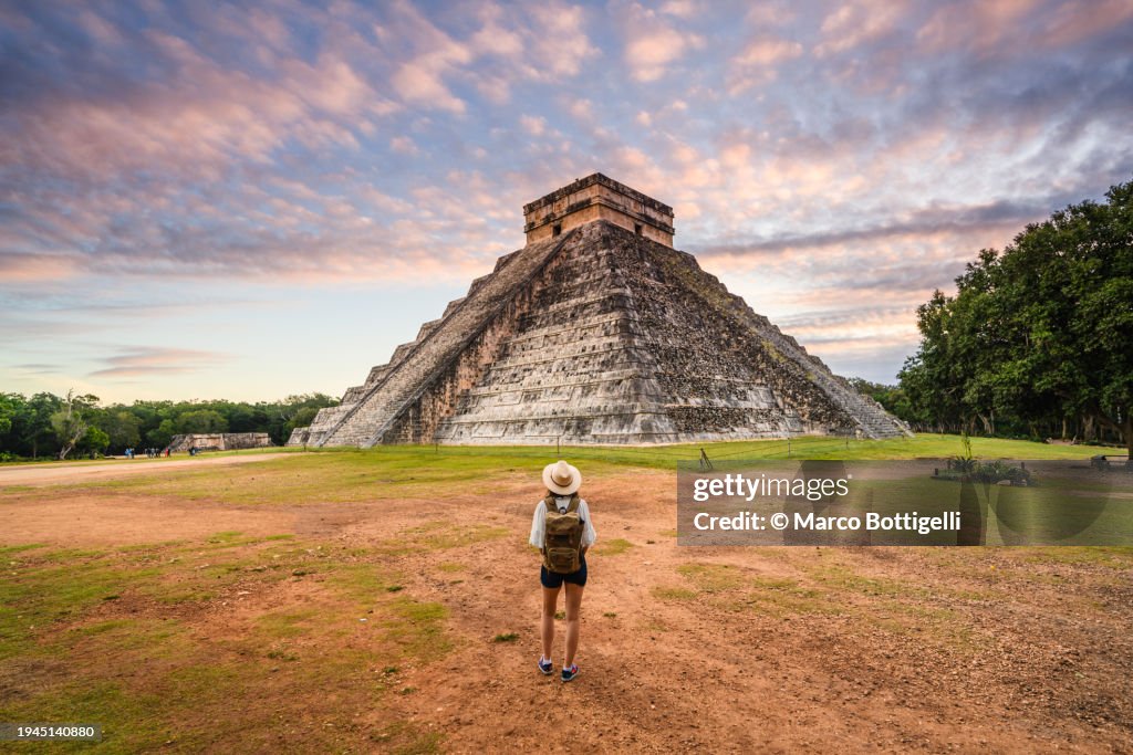 Woman admiring Chichen Itza's Kukulkan pyramid at sunrise, Mexico