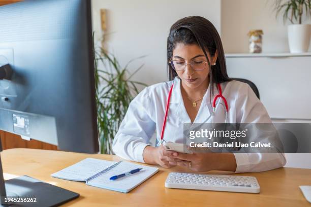 female doctor is using mobile phone while resting - casa calvet stock pictures, royalty-free photos & images