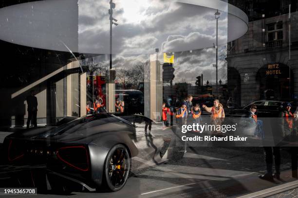 Schoolchildren admire a Lotus all-electric Evija sports car which is positioned in the window of the British motoring brand's showroom on Piccadilly,...