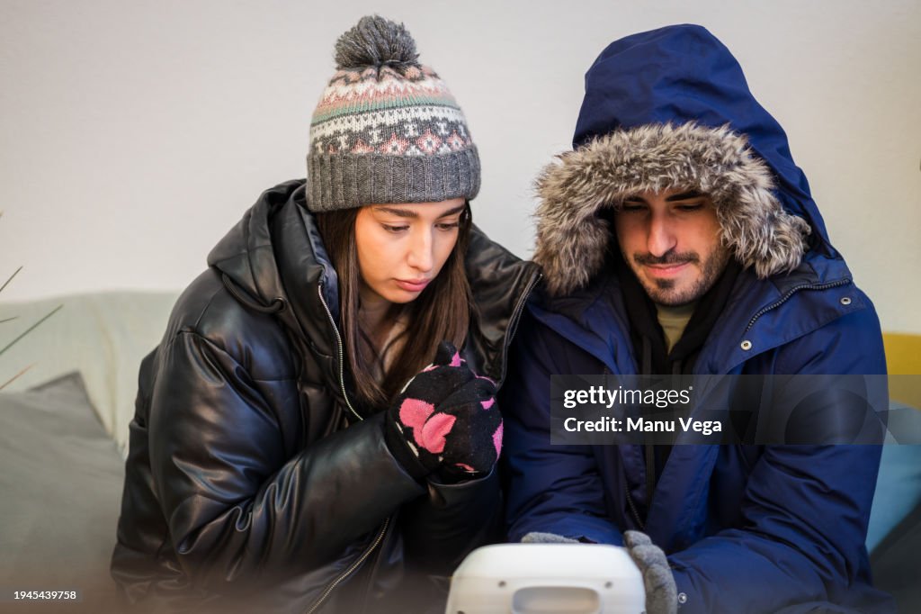 Couple sitting in the living room in front of the heater on a winter day.