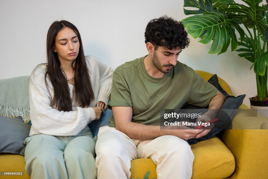 Young couple sitting on sofa in apartment living room.