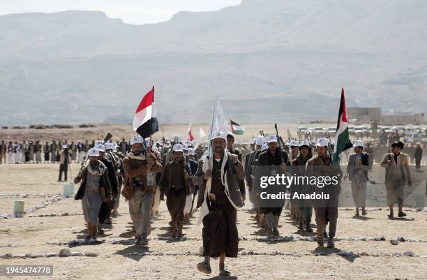 Houthi supporters gather as they carry heavy weapons and chanting slogans to stage a parade and demonstrate against the US and UK attacks in the Bani...