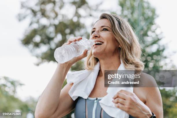 portrait of a sporty woman drinking water - sportkleidung stock-fotos und bilder