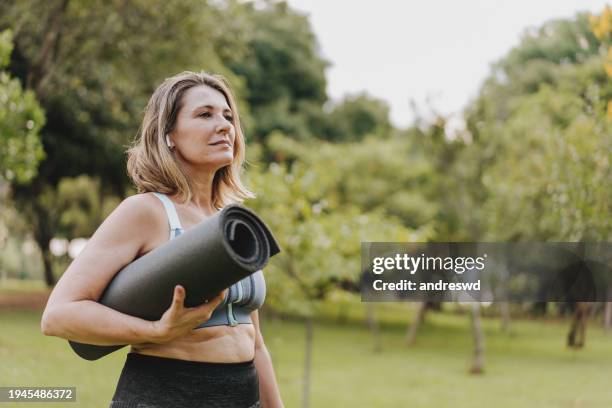 mature woman going to practice physical exercise with exercise mat - yoga rug stock pictures, royalty-free photos & images