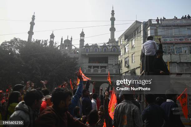 People are chanting slogans and waving flags with a portrait of the Hindu god Lord Ram during a procession to celebrate the opening of the Hindu Ram...