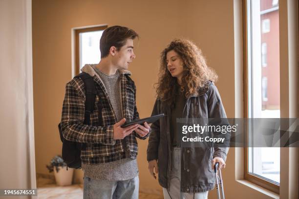 young couple arriving at hotel and looking at digital tablet in the hallway - man in suite holding tablet stockfoto's en -beelden