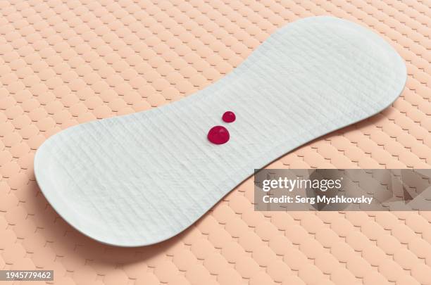 one sanitary pad with red drops on an orange background. - poroso foto e immagini stock