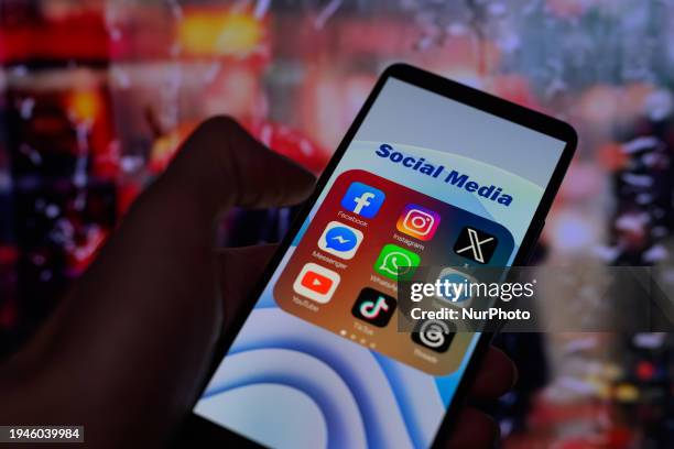 Icons for various social media apps, including Facebook, Instagram, X, Threads, and TikTok, are being displayed on a smartphone in this photo...