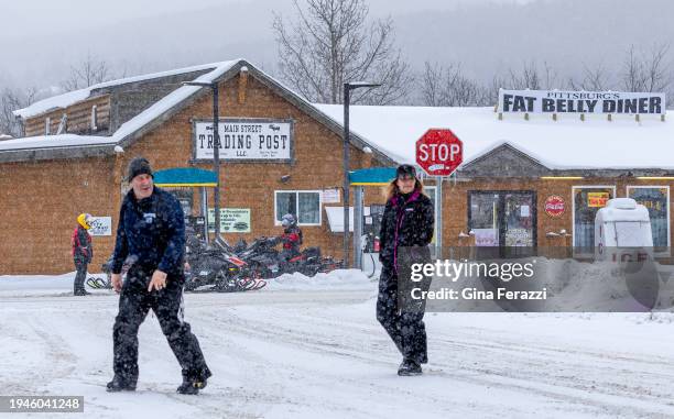 Snowmobilers gas up at the Main Street Trading Post while others walk across the snowy street for food at a local restaurant on January 20, 2024 in...