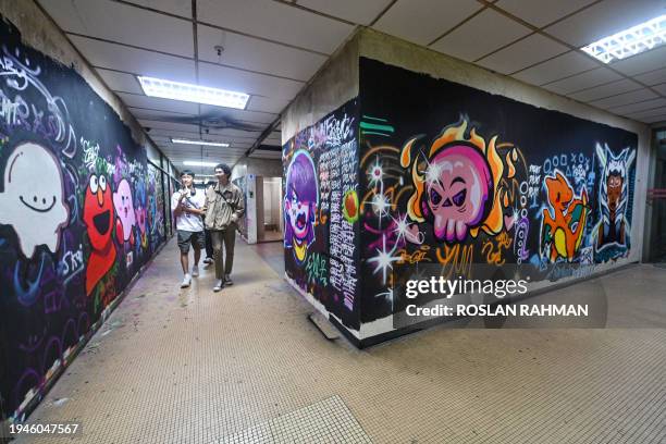 In this photograph taken on January 19 people walk past murals and grafitti at the Peace Centre, an abandoned mall turned into an unexpected art...