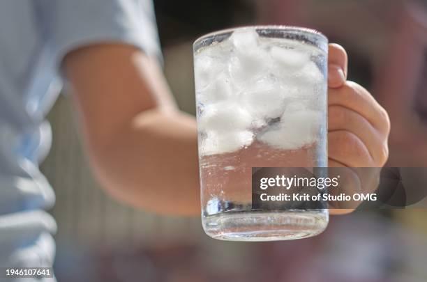 cropped view woman holding a mug of cold water - eiswürfel stock-fotos und bilder