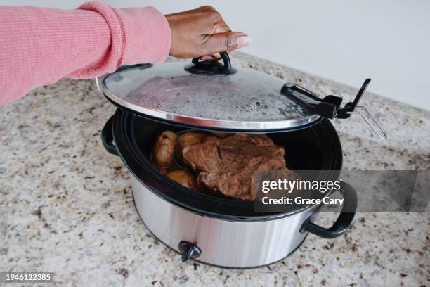 woman checks on food in slow cooker - pot roast stock pictures, royalty-free photos & images