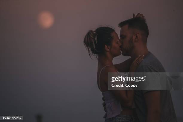 young couple kissing, in the background moon - moonlight lovers stock pictures, royalty-free photos & images