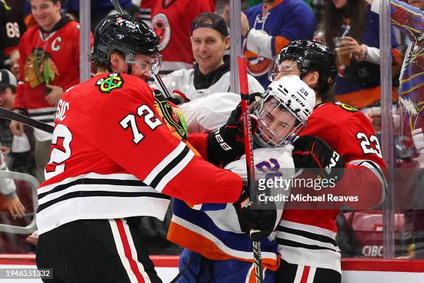 Alexander Romanov of the New York Islanders scuffles with Alex Vlasic and Philipp Kurashev of the Chicago Blackhawks during the first period at the...