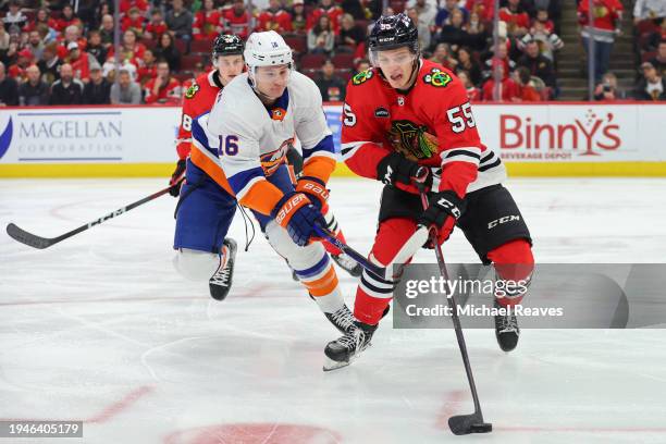 Kevin Korchinski of the Chicago Blackhawks controls the puck against Julien Gauthier of the New York Islanders during the first period at the United...