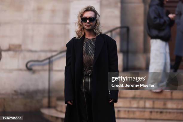 Bill Kaulitz is seen wearing a glittery silver shirt, a black long wool coat, leather pants, black sunglasses and black boots by 032C show during the...