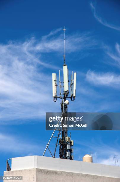 cellular phone repeater tower mast on a building roof top - repeater stock pictures, royalty-free photos & images