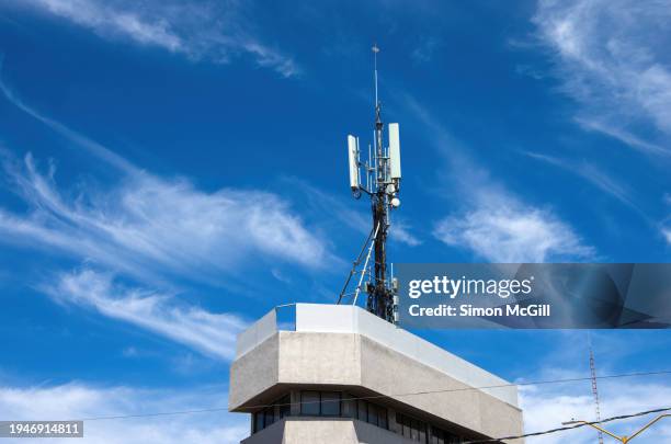 cellular phone repeater tower mast on a building roof top - repeater stock pictures, royalty-free photos & images