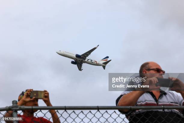 People take phone photos from Shep’s Mound, a plane spotters’ lookout as a Rex plane takes off from Sydney Airport on January 20, 2024 in Sydney,...