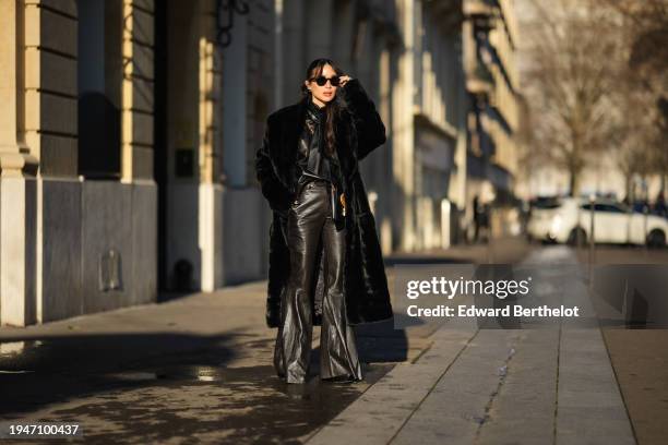 Heart Evangelista wears sunglasses, earrings, a black long fluffy winter faux fur coat, a black leather jacket, black leather flared pants, a...