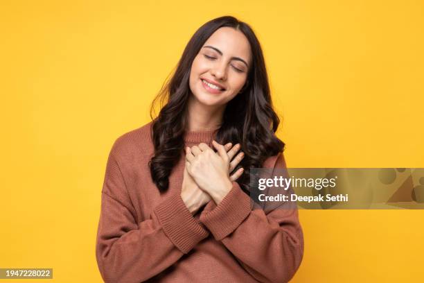 photo of young women in winter wear standing on yellow background stock photo - truehearts stock pictures, royalty-free photos & images