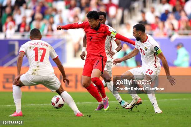Son Heung-min of South Korea is put under pressure by Salem Al-Ajalin and Ihsan Haddad of Jordan during the AFC Asian Cup Group E match between...
