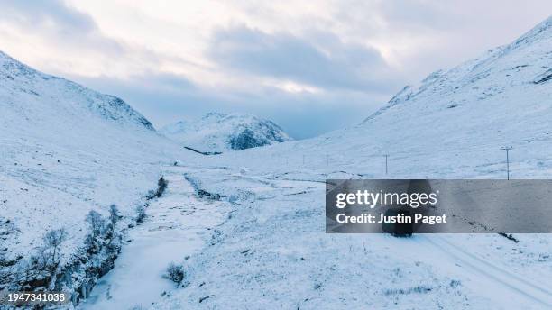 drone/aerial view of a campervan parked beside a snow covered road in the scottish highlands - justin van groen stock pictures, royalty-free photos & images