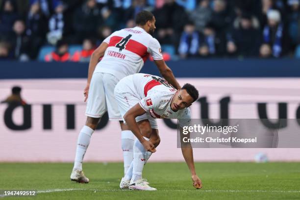 Jamie Leweling of VfB Stuttgart discards chocolate coins thrown onto the pitch by fans protesting during the Bundesliga match between VfL Bochum 1848...