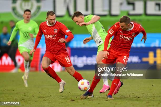 Yannick Gerhardt of VfL Wolfsburg is challenged by Jonas Foehrenbach and Adrian Beck of 1.FC Heidenheim during the Bundesliga match between 1. FC...