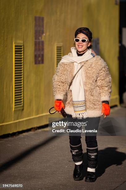 Guest wears beige fur jacket, black pants, beige scarf, Chanel leg warmers, outside Paul Smith, during the Menswear Fall/Winter 2024/2025 as part of...